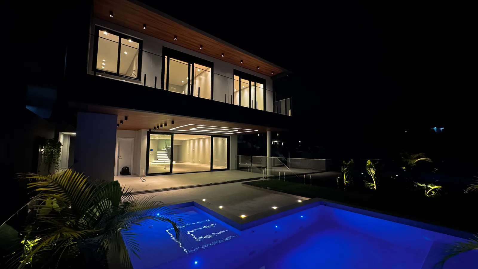 Fachada iluminada da Casa Van Gogh à noite, com a piscina em destaque