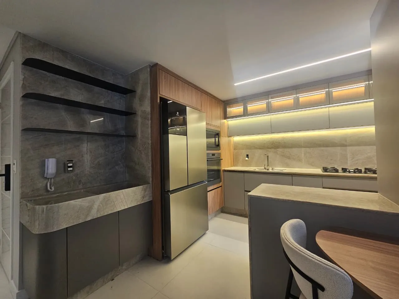 Cozinha com ilha, adega e acabamento em tons sóbrios